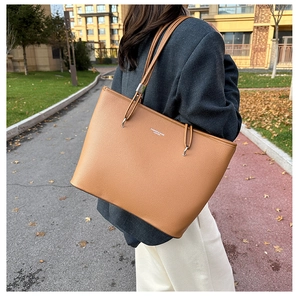 Dettaglio borsa tote in pelle marrone caramello con trama litchi sulla spalla
