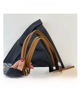 Dettaglio dei manici in pelle marrone rinforzati su borsa tote in pelle martellata