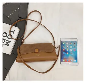 Detailed top view of caramel leather shoulder bag with metallic clasp on textured fabric