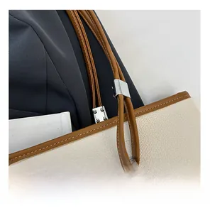 Dettaglio della borsa tote bicolore in pelle con grana e fibbie in metallo argento