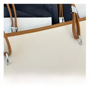 Dettaglio della borsa in pelle litchi bianco sporco con tracolla marrone e anelli