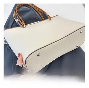 Dettaglio della borsa tote in pelle beige con manici marroni e piedini in metallo argento