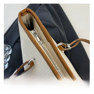 Dettaglio della cerniera in metallo e finiture in pelle marrone della borsa beige