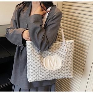 Détail du sac cabas blanc avec motif M embossé et bandoulière porté par un mannequin