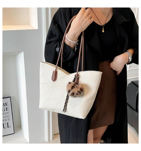 Detail of white lychee leather tote bag with brown straps and leopard fur ball charm