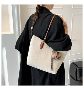 Close-up of white lychee texture leather bucket bag with brown strap and leopard fur charm