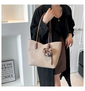 Detail view of beige lychee texture leather tote bag with a leopard heart charm pendant