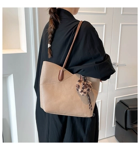 Detail of beige lychee leather tote bag with a leopard print plush ball charm on shoulder