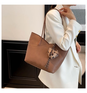 Detail of caramel leather tote bag with leopard heart charm and ample capacity