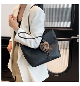 Close-up of black lychee grain leather tote bag with a leopard print plush pendant charm