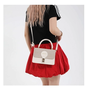 Close-up of cream crossbody bag with woven texture flap and metallic twist lock clasp