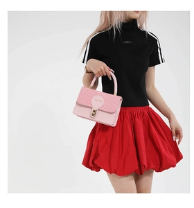 Detail of pink fashion handbag featuring woven patchwork texture and golden square lock