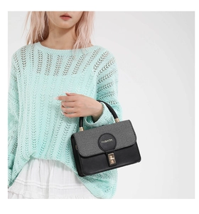 Detail of vintage square crossbody bag with grey fabric flap and golden lock on model