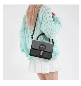 Detail view of the black retro square bag with golden turn-lock and adjustable strap