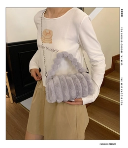 Détail d'un sac en peluche gris avec texture rayée et poignée en billes douces