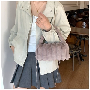 Détail du sac peluche rose avec texture ondulée et poignée ornée d'un pompon doux