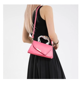 Detail of hot pink crossbody bag with unique silver heart-shaped metal handle and strap