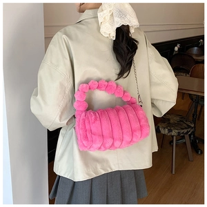 Détail du sac oreiller en peluche rose avec poignée à pompons et bandoulière en chaîne