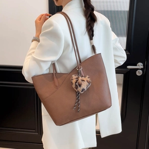 Brown leather tote bag with heart charm shown on model in white blazer for work