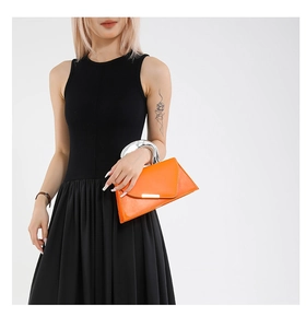 Detail of bright orange geometric crossbody bag with a circular silver metal handle