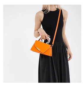 Detail of orange handbag with unique silver metal handle and contrast stitching