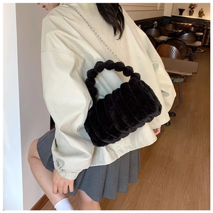 Détail du sac bandoulière en peluche noire avec poignée sphérique et texture douce