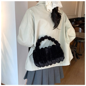 Détail d'un sac bandoulière en fausse fourrure noire avec chaîne argentée dans un café