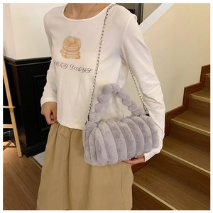 Détail du sac polochon en fausse fourrure grise avec design cylindrique et chaîne argent