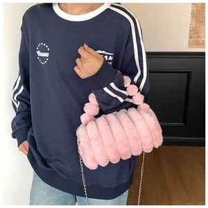 Gros plan du sac oreiller en peluche rose avec bandes matelassées et chaîne en métal