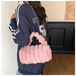 Sac bandoulière cylindrique en peluche rose avec chaîne en métal porté par un mannequin