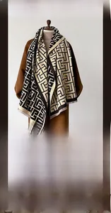 Close-up of thick winter scarf featuring black and beige geometric pattern and soft tassels