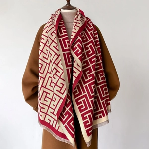 Detail of red and beige geometric pashmina scarf with fringe on brown wool coat