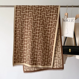 Detail view of retro geometric pattern and short tassels on a brown knit shawl