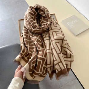Detail of winter scarf featuring brown and beige geometric jacquard pattern with tassels