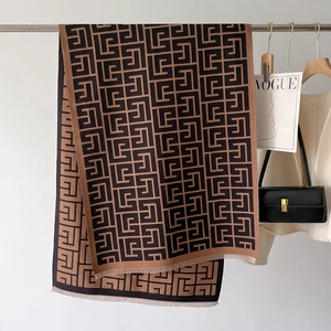 Detail of cashmere-like scarf with brown geometric patterns and fine fringe edges