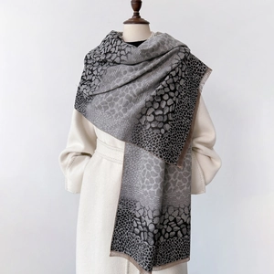 Détail d'une écharpe léopard douce avec dégradé de gris, texture cachemire et franges