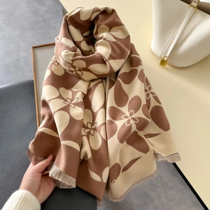 Dettaglio dello scialle in maglia spessa con stampa floreale e nappe di frangia