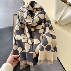 Dettaglio di sciarpa in maglia floreale con nappe e trama spessa di qualità