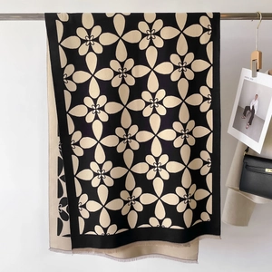 Dettaglio della sciarpa in maglia floreale con frange e una borsa nera per lo styling