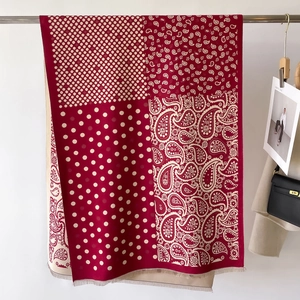Dettaglio di sciarpa bordeaux con motivi paisley e pois con bordi a frange morbide