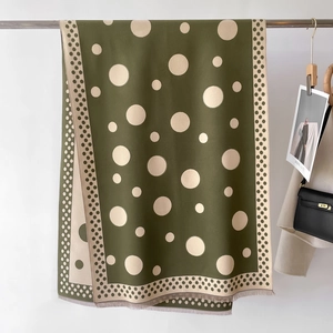Close-up of olive green polka dot cashmere shawl with tassels and spring date styling
