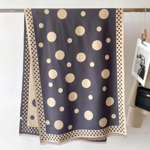Close-up of thick charcoal grey cashmere scarf with beige polka dots and fringe details