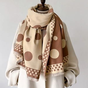 Close-up of a thick polka dot scarf in beige and brown with elegant fringe details