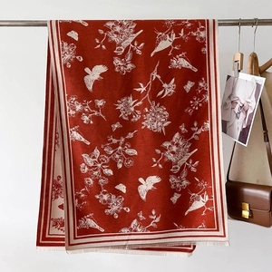 Detailed macro view of brick red cashmere scarf with white bird pattern and fringe