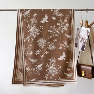 Detail of coffee brown cashmere-feel scarf with white floral and butterfly prints and tassels