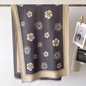 Detail of cashmere-like scarf showing camellia patterns, dual-tone design and soft tassels