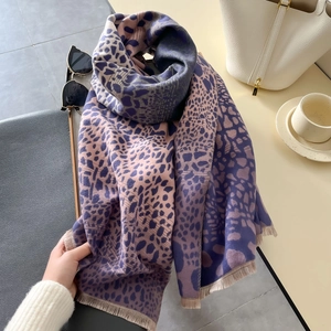 Dettaglio della sciarpa spessa leopardata viola con frange e accessori lifestyle