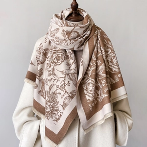 Détail d'un châle imprimé fleurs et pie vintage avec franges sur tissu beige