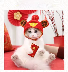Macro view of red plush pet New Year hat featuring traditional gold embroidery and ingot detail