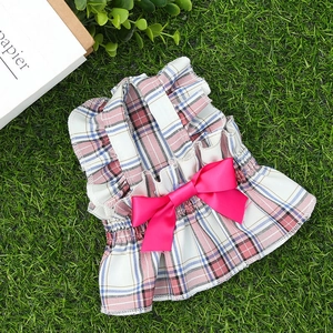 Détail d'une robe pour chien à carreaux roses avec un grand nœud sur fond d'herbe